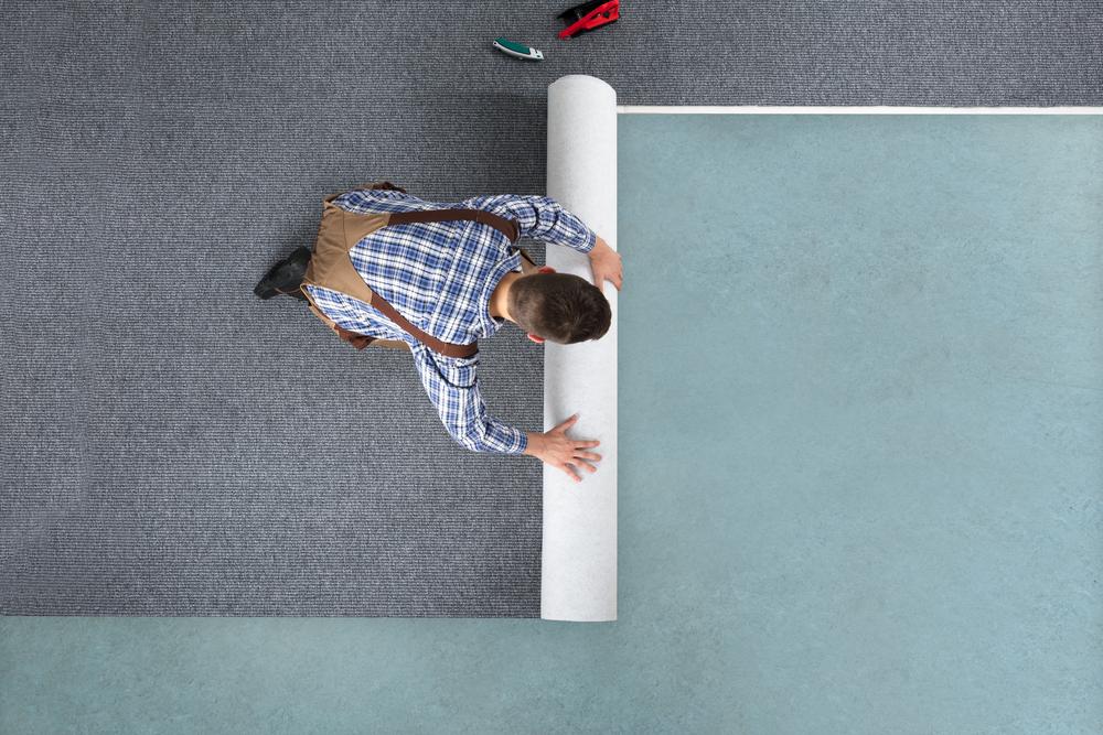 Man rolling carpet for installation | Flooring Direct